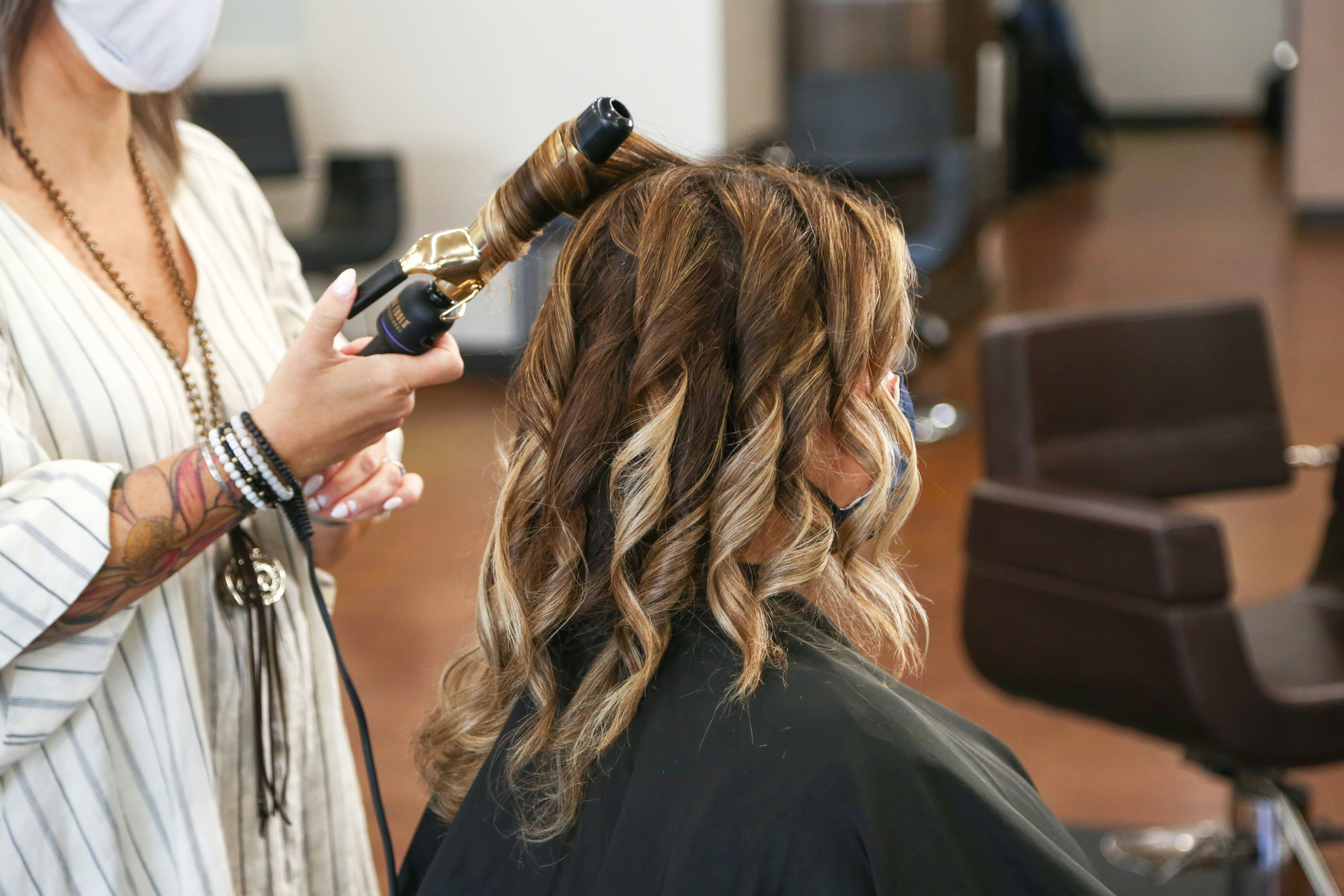 woman with long hair is having her hair styled by a professional